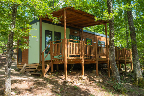 Moderne hytte med træterrasse i Chianti Glamping Resort, omgivet af skov, ideel til glampingferien.