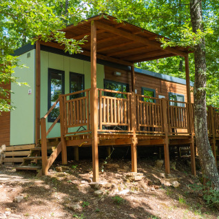 Chalet moderne avec terrasse en bois au Chianti Glamping Resort, entouré d’arbres, idéal pour le glamping.