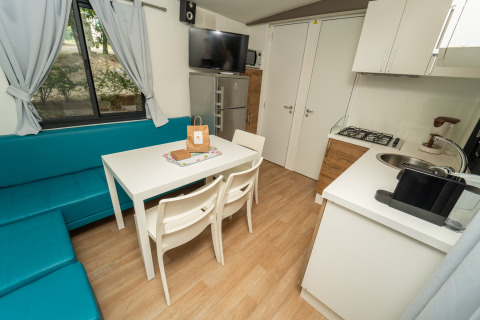 Moderne cottage bij Chianti Glamping Resort met eettafel, keukenblok, blauwe bank en televisie.