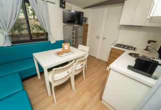 Gemütliches Cottage-Interieur im Chianti Glamping Resort mit Essecke, Küchenzeile und Ecksofa.