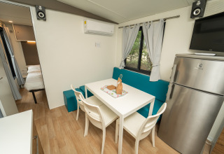 Interieur van een modern glampinghuisje bij Chianti Glamping Resort met eettafel, koelkast en slaapkamer.