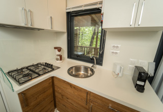 Moderne kitchenette bij Chianti Glamping Resort met gaskookplaat, wasbak en uitzicht op de natuur.