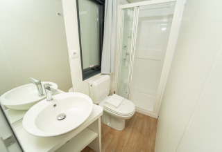 Baño moderno en Chianti Glamping Resort - Cottages Toscane con ducha, inodoro y lavabo elegante.