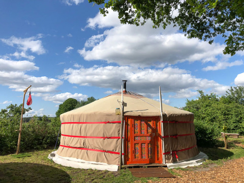 Una yurta tradizionale al Glamping 't Buitenland - Yurts Brabant sotto un cielo blu con nuvole.
