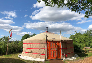 A traditional yurt at Glamping 't Buitenland - Yurts Brabant, set under a blue sky with clouds.