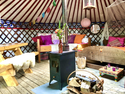 Gemütlich eingerichtetes Glamping-Yurt bei 'Glamping 't Buitenland - Yurts Brabant' mit buntem Interieur.