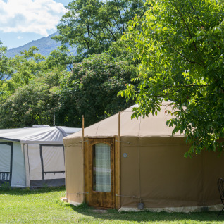 Glamping-accommodatie met Mongoolse yurt en tent omringd door bomen op Camping Bellinzona in Zwitserland.