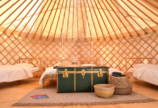 Binnenaanzicht van een gezellige Mongoolse yurt op Camping Bellinzona, Zwitserland, met vier bedden.