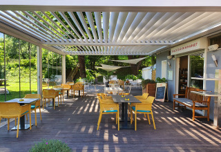 Outdoor dining area at Camping Bellinzona - Mongoolse Yurt Zwitserland with yellow chairs and green scenery.