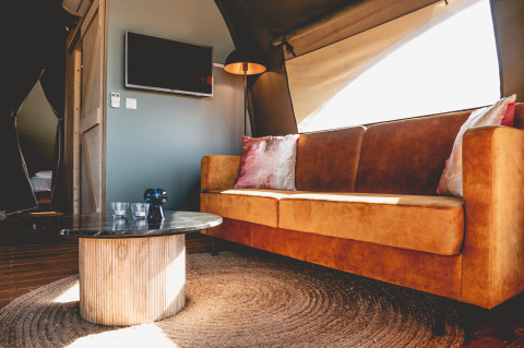 Interieur van een luxe glamping lodgetent in Camping De Bovenberg, met gezellige zetel en eigentijdse inrichting.
