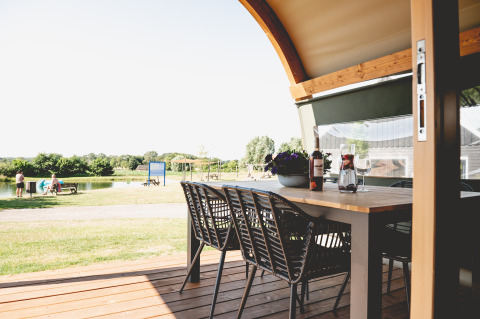 Uitzicht vanaf een glamping lodgetent-terras bij Camping De Bovenberg met tafel, stoelen en vijver
