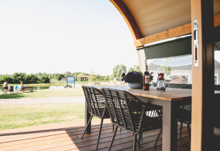 View from a glamping lodge tent terrace at Camping De Bovenberg with table, chairs and pond in background