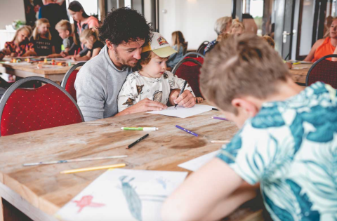 Famiglie si divertono a disegnare insieme in un'area comune al Camping De Bovenberg – Lodgetenten Twente.