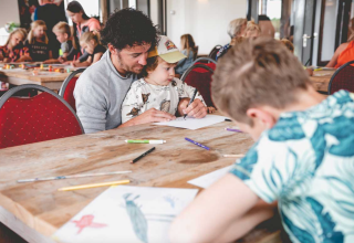 Familien genießen gemeinsam Malaktivitäten im Gemeinschaftsraum von Camping De Bovenberg – Lodgetenten Twente.