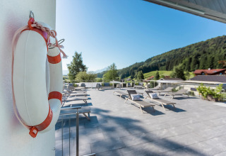 Terrasse ensoleillée avec chaises longues et vue sur les montagnes à Camp MondSeeLand - Kampeerhutten Oostenrijk.
