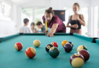 Personas juegan billar en un ambiente relajado en Camp MondSeeLand - Kampeerhutten Oostenrijk durante el glamping.
