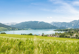 Panoramisch uitzicht op Camp MondSeeLand in Oostenrijk, met groene weiden, meer en bergen.