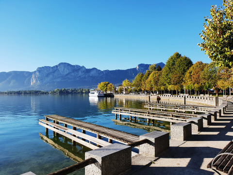 Vista del lago e delle montagne al Camp MondSeeLand Kampeerhutten Austria con pontile e alberi sul lungomare.