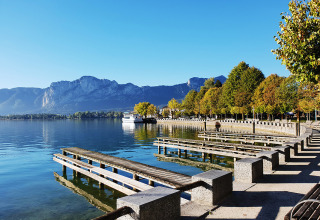 Vue sur le lac et les montagnes au Camp MondSeeLand Kampeerhutten Autriche avec jetée et arbres riverains.