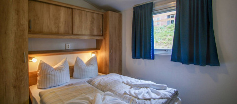 Gezellige glampingkamer met dubbel bed, houten kast en raam in Vakantiepark Havelberge.