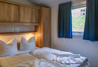 Camera glamping accogliente con letto matrimoniale, mobili in legno e finestra al Vakantiepark Havelberge.