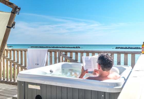 Ein Mann entspannt im Whirlpool mit Meeresblick bei Villa Alwin Beach Resort – Luxuszelte in Le Marche.