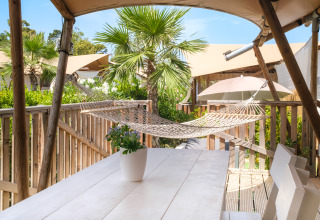 Terrazza accogliente con amaca, tavolo in legno e palme al Villa Alwin Beach Resort, glamping Le Marche.