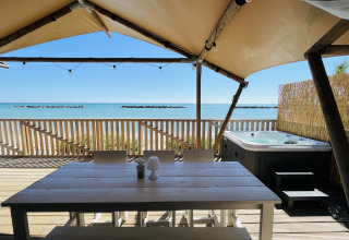 Terraza de tienda glamping de lujo con mesa y jacuzzi frente a la playa en Villa Alwin Beach Resort.
