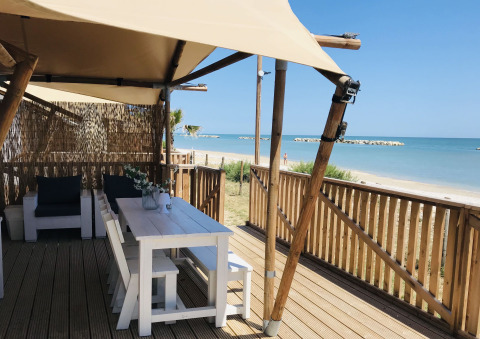 Glampingindkvartering ved stranden med hvide møbler og havudsigt på Villa Alwin Beach Resort i Le Marche.