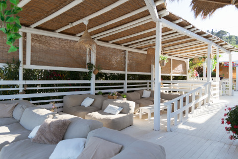 Outdoor lounge area with cozy sofas at Villa Alwin Beach Resort, covered and surrounded by lush greenery.