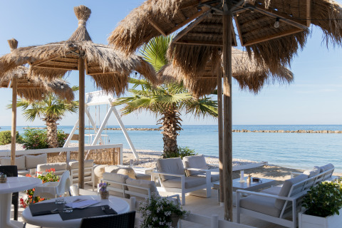 Loungehoek met rieten parasols en uitzicht op zee bij Villa Alwin Beach Resort aan het strand in Le Marche.