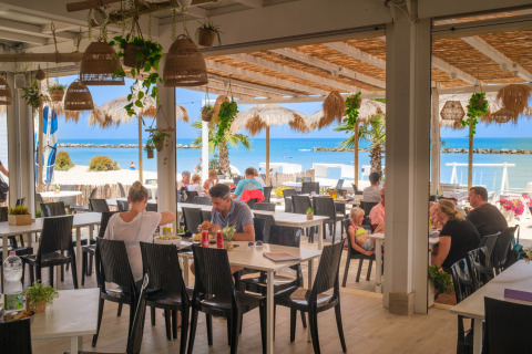 Área de comedor al aire libre en Villa Alwin Beach Resort con vistas a la playa y huéspedes en Le Marche, Italia.