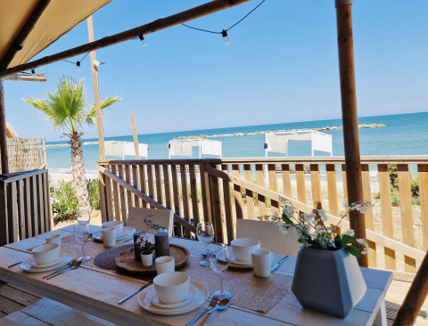 Terrazza coperta al Villa Alwin Beach Resort con tavolo apparecchiato e vista mare e spiaggia nelle Marche.