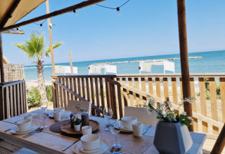 Terrasse couverte au Villa Alwin Beach Resort avec table dressée, vue sur la plage et la mer à Le Marche.