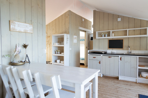 Cuisine et salle à manger glamping de luxe à Villa Alwin Beach Resort, mobilier blanc et lambris bois.