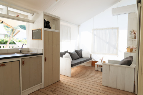 Gemütliche Glamping-Unterkunft am Strand in Le Marche mit Sofa, Küchenzeile und Holzboden.