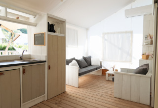 Alojamiento glamping acogedor en la playa en Le Marche con sofá, cocineta y suelos de madera.