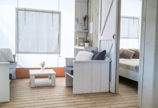 Interieur van luxe lodgetent bij Villa Alwin Beach Resort met stijlvolle witte houten meubels aan het strand.