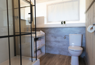 Salle de bain moderne avec douche, toilettes et lavabo au glamping Villa Alwin Beach Resort sur la plage Le Marche.
