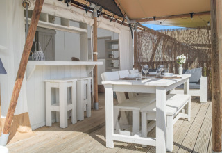 Outdoor-Essbereich mit weißen Holzmöbeln in einem Glamping-Zelt im Villa Alwin Beach Resort, Le Marche.