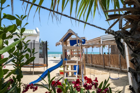 Speelzone met glijbaan en schommel aan het strand bij luxe lodgetenten van Villa Alwin Beach Resort.