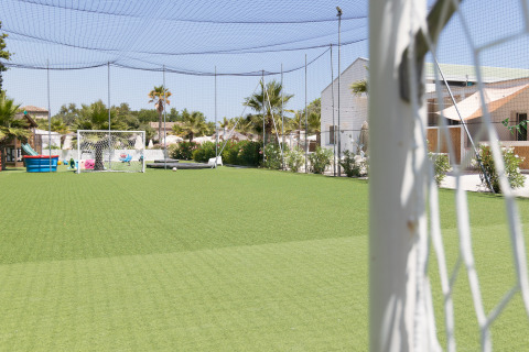 Voetbalveld met kunstgras bij Villa Alwin Beach Resort, omgeven door luxe lodgetenten en palmbomen.