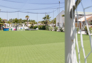 Voetbalveld met kunstgras bij Villa Alwin Beach Resort, omgeven door luxe lodgetenten en palmbomen.