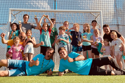 Enfants et adultes heureux célèbrent sur un terrain de football à Villa Alwin Beach Resort, glamping Le Marche, Italie.
