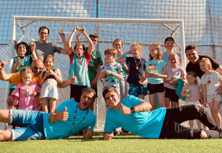 Kinder und Erwachsene jubeln auf einem Fußballplatz bei Villa Alwin Beach Resort, Glamping in Le Marche, Italien.
