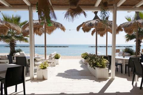 Strandzicht vanuit Villa Alwin Beach Resort in Le Marche met luxe lodgetenten en gezellige zitplekken.