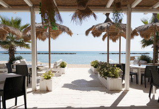 Strandzicht vanuit Villa Alwin Beach Resort in Le Marche met luxe lodgetenten en gezellige zitplekken.