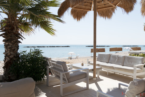 Outdoor lounge with comfortable sofas overlooking the sandy beach at Villa Alwin Beach Resort in Le Marche.