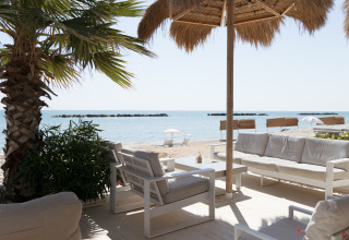 Loungehoek met comfortabele banken uitkijkend op het strand bij Villa Alwin Beach Resort in Le Marche.