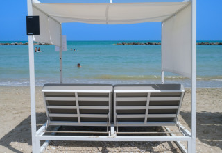 Vista de la playa desde tienda de lujo en Villa Alwin Beach Resort en Le Marche, Italia, con tumbonas.